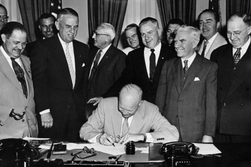 Eisenhower signs document in Oval Office