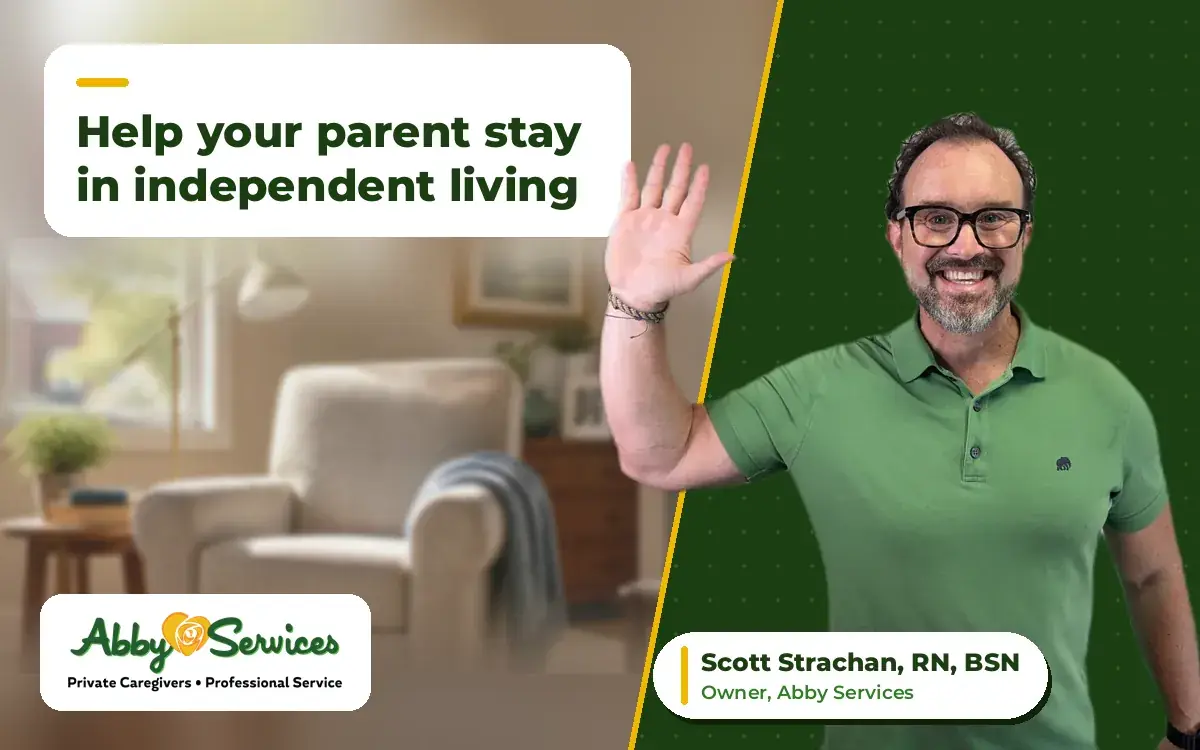 Scott Strachan, RN, BSN, owner of Abby Services, waving hello, with a bright senior apartment living room with an armchair and reading lamp in the background